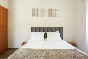 A neatly made bed with a grey headboard, white pillows, and a grey textured rug. - AL - Vic Center House (Sao Vicente)