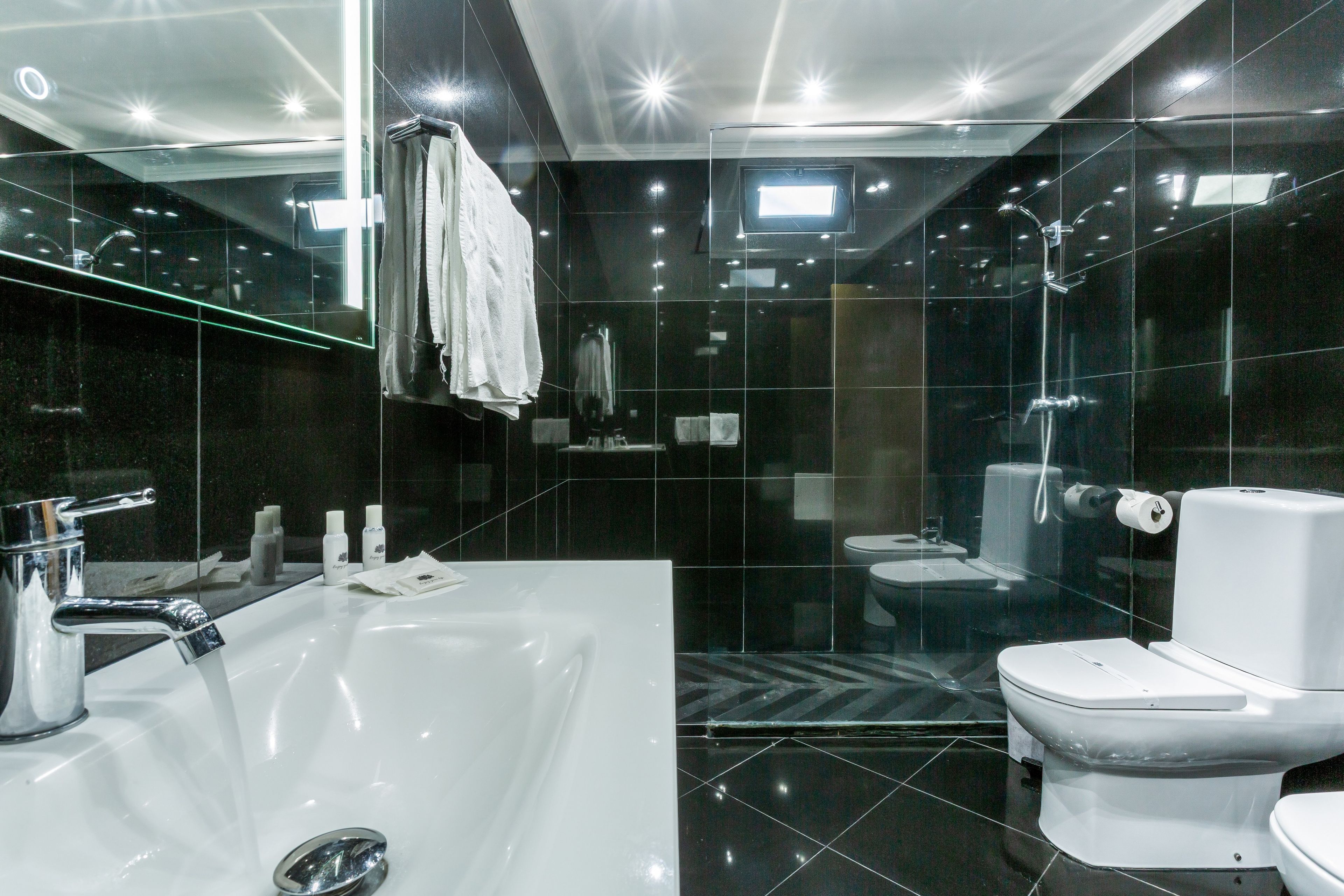 Een moderne badkamer met een groot, wit bad, een apart toilet en een douchecabine met glazen wanden.