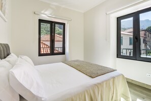 Ein Hotelzimmer mit Bett, Fenster mit Blick auf Gebäude und einem Balkon.