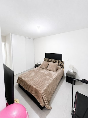 A bedroom with a bed, bedside tables, a TV, and a pink exercise ball. - New apartment, terrace & parking – Résidence Boréal, Montpellier (Monptellier)