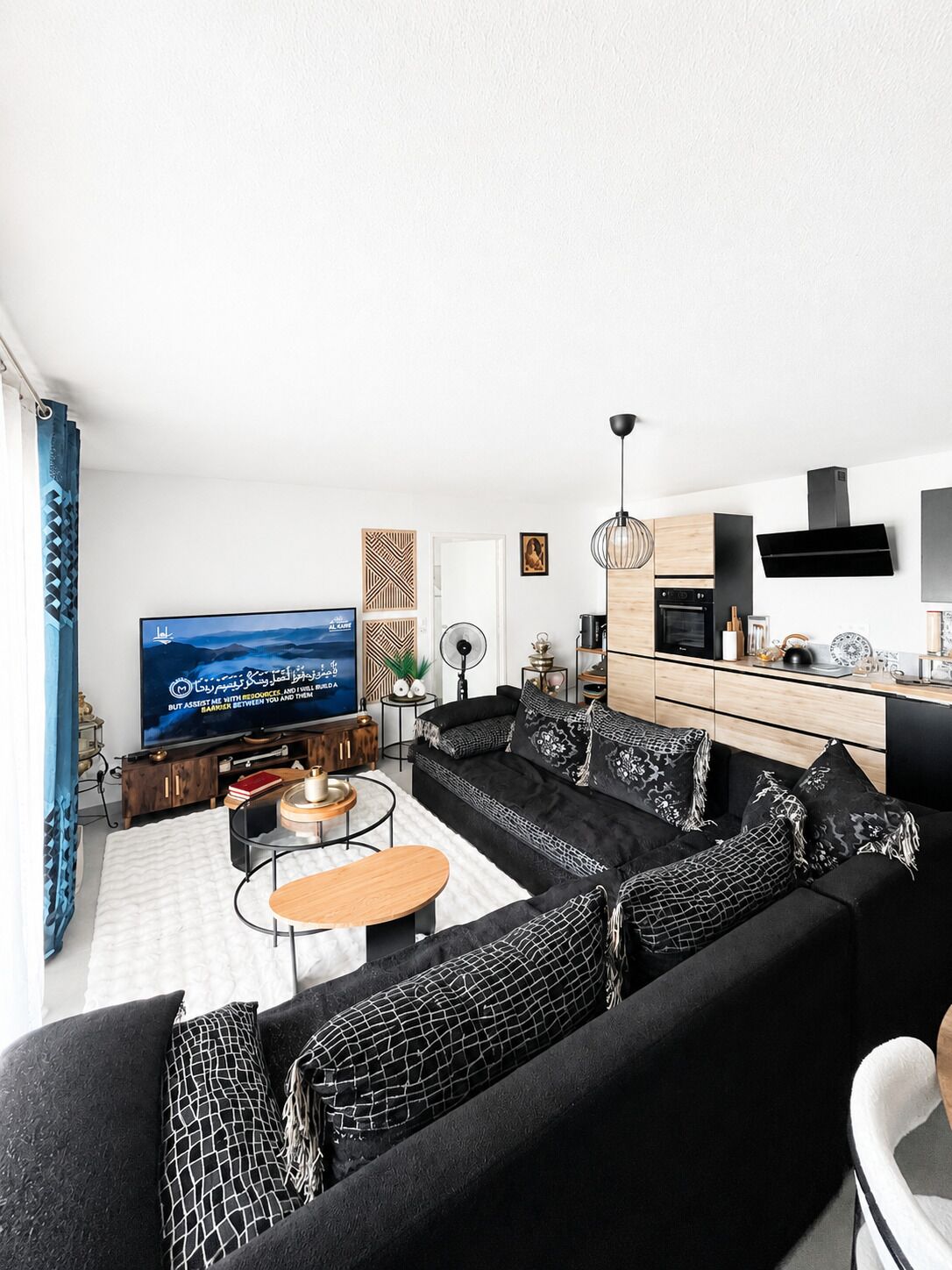 Un salon moderne avec un canapé noir, une table basse et un téléviseur à écran plat.