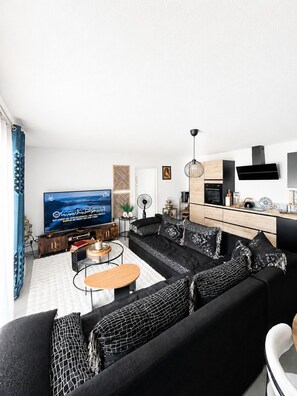 A modern living room with a black sofa, a coffee table, and a flat-screen TV. - New apartment, terrace & parking – Résidence Boréal, Montpellier (Monptellier)