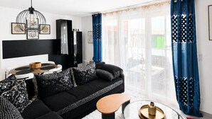 Ein modernes Wohnzimmer mit einer schwarzen Couch, einem Glastisch und einer schwarzen TV-Konsole.