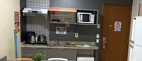 A compact kitchenette with a microwave, kettle, and coffee maker.