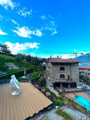 Ein Gebäude aus Stein mit rotem Ziegeldach, einer Holzdachterrasse und einem Swimmingpool.