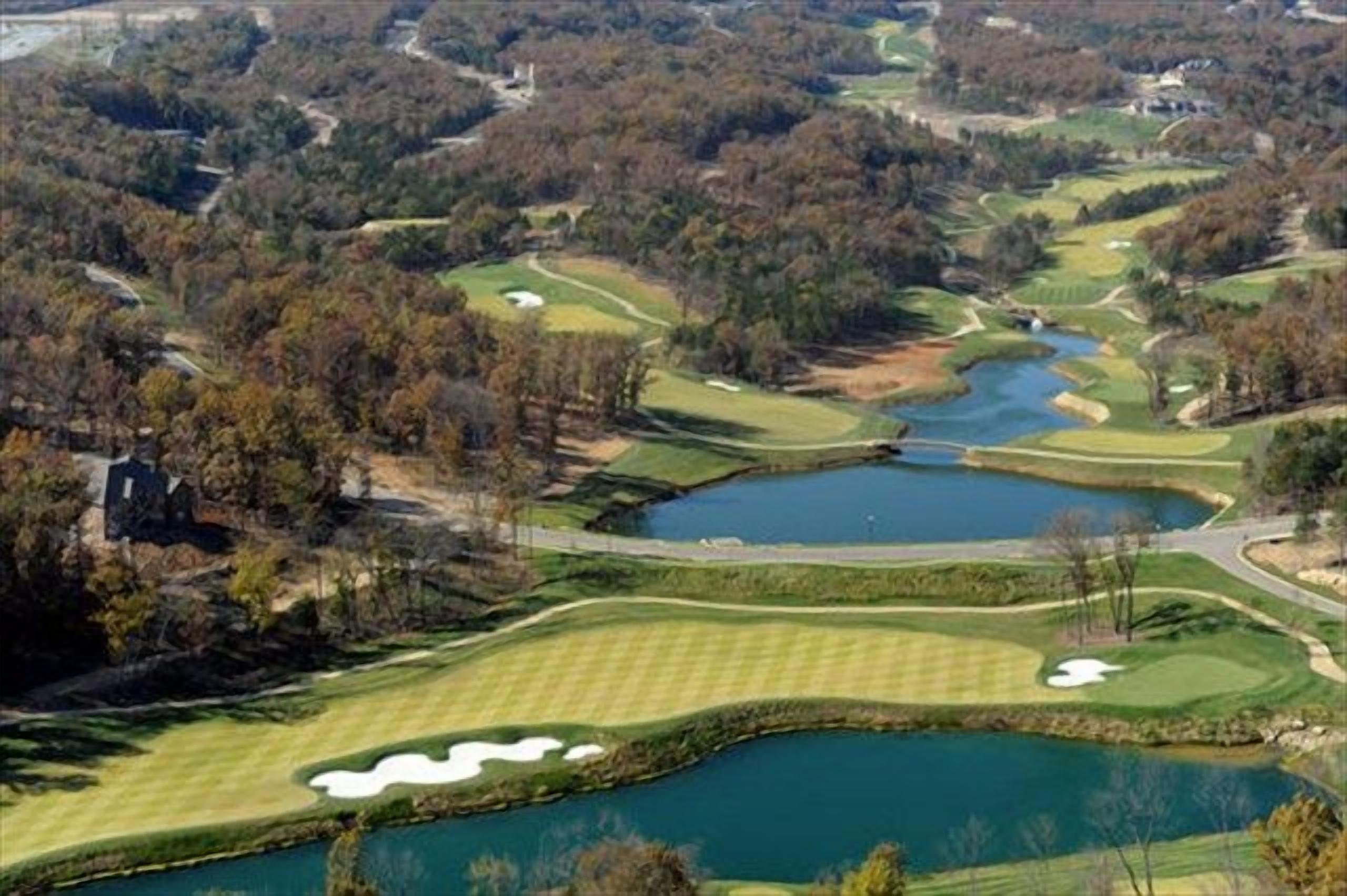 Ein Golfplatz mit mehreren Teichen und einer Brücke.