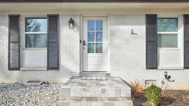 A residential building with a white brick facade, a front door with a window, and shutters on both sides. - Luxury, Romantic, Unique Retreat (Norcross)