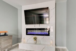 A modern living room with a flat-screen TV mounted above a built-in fireplace.