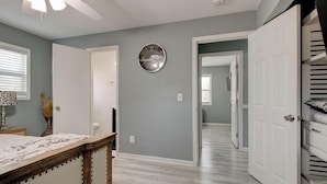 A room with a wooden bed, a ceiling fan, a clock, and a hallway leading to another room. - Luxury, Romantic, Unique Retreat (Norcross)
