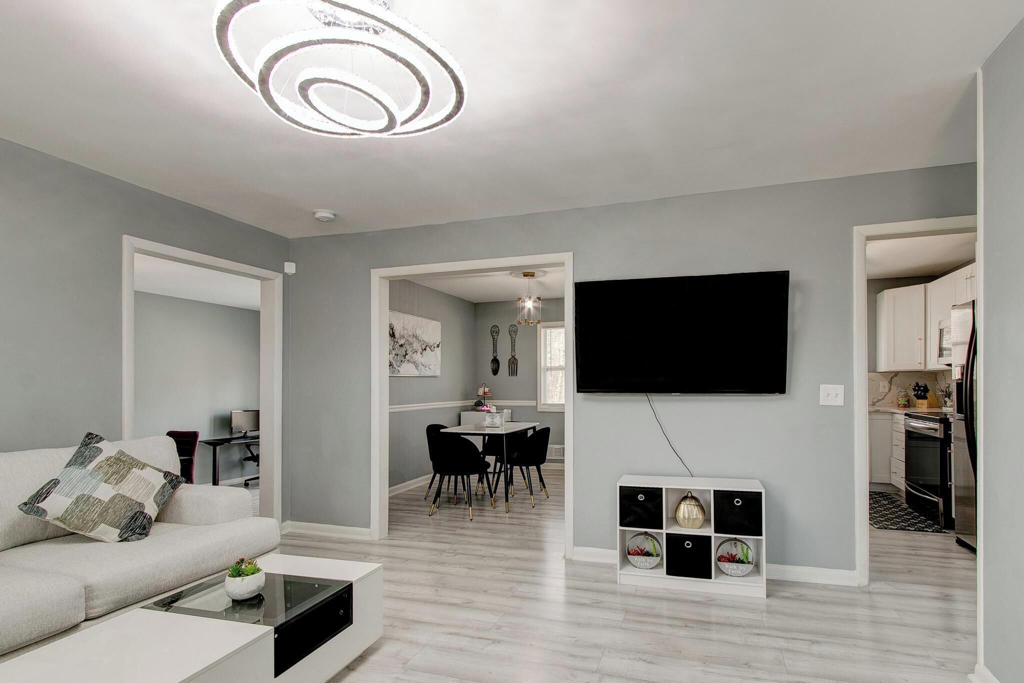 A modern living room with a sofa, coffee table, and a flat-screen TV mounted on the wall.