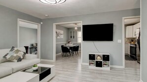A modern living room with a sofa, coffee table, and a flat-screen TV mounted on the wall. - Luxury, Romantic, Unique Retreat (Norcross)
