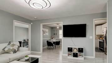 A modern living room with a sofa, coffee table, and a flat-screen TV mounted on the wall.