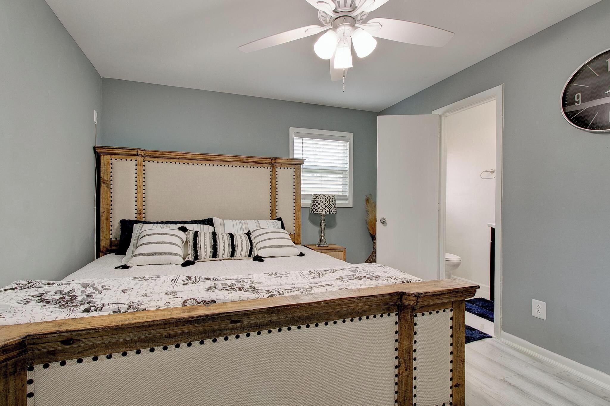 A bedroom with a bed, a ceiling fan, a window, and a door.