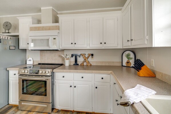 A kitchen with white cabinets, a stainless steel stove, and a microwave.