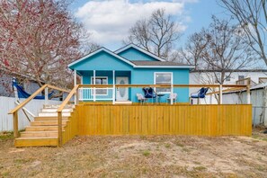 A two-story house with a blue exterior, a wooden deck, and a fenced backyard.