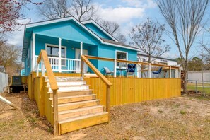 A two-story house with a blue exterior, wooden stairs, and a fenced yard.