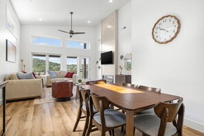 A spacious living area with a dining table, sofas, and a television.
