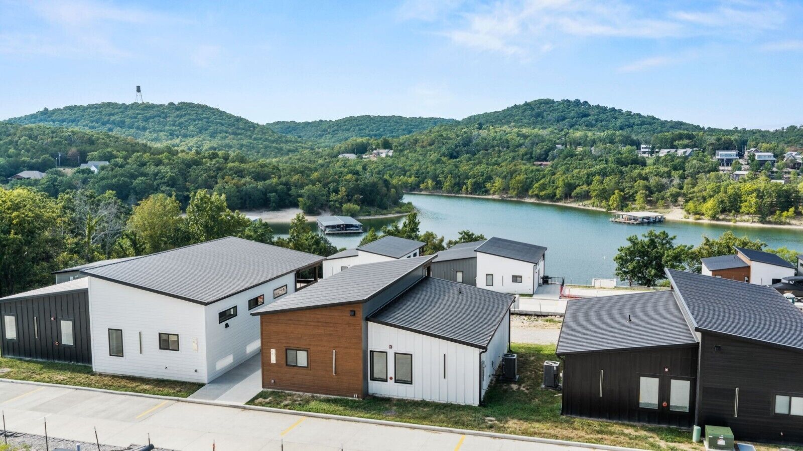 A residential area with modern houses, a lake, and hills in the background.