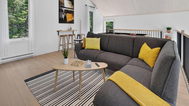 A modern living room with a sectional sofa, a coffee table, and a view of the outdoors. - Jadeheim - Chalet 12 pers Spa et Sauna prives - Resort pres de Quebec (Shannon)