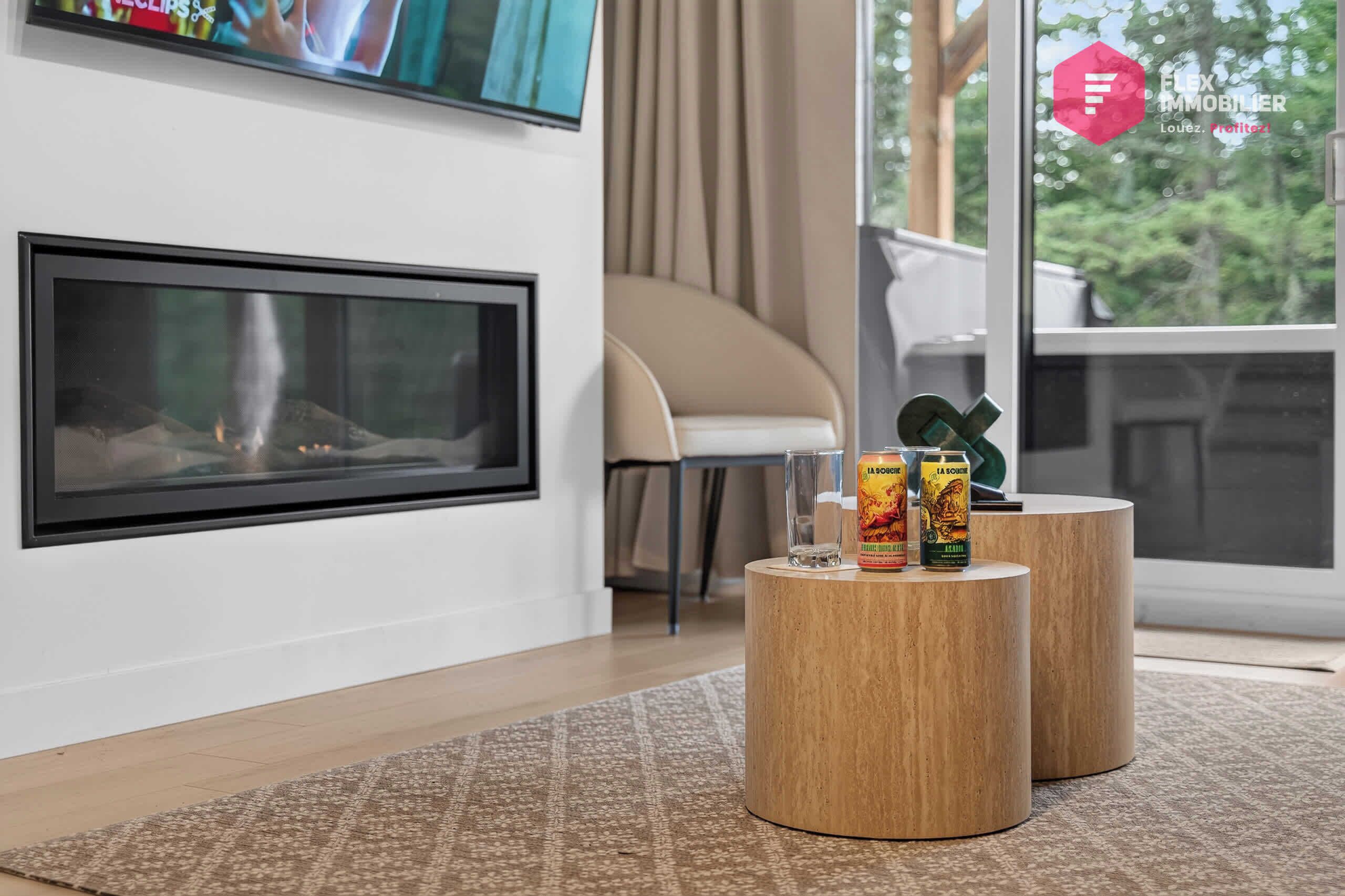 A modern living room with a fireplace, a sofa, and a coffee table with two cans of La Soirée.