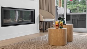 A modern living room with a fireplace, a sofa, and a coffee table with two cans of La Soirée. - Jadeheim - Chalet 12 pers Spa et Sauna prives - Resort pres de Quebec (Shannon)