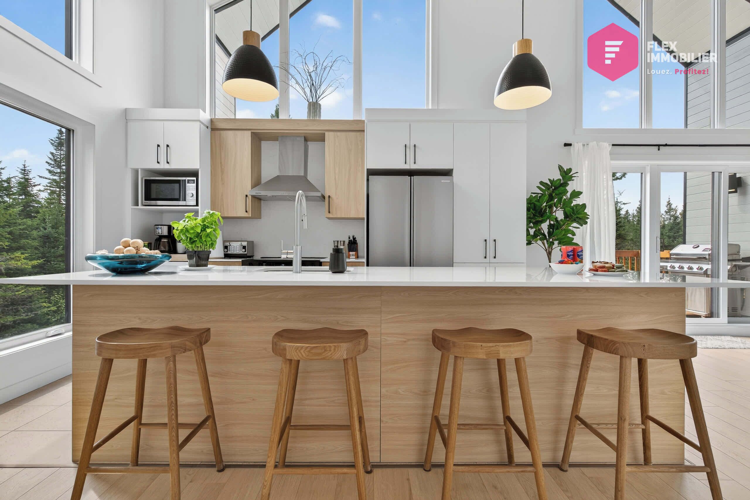 Una cocina moderna con una isla grande, taburetes de madera e iluminación colgante.