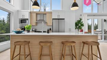 Una cocina moderna con una isla grande, taburetes de madera e iluminación colgante.
