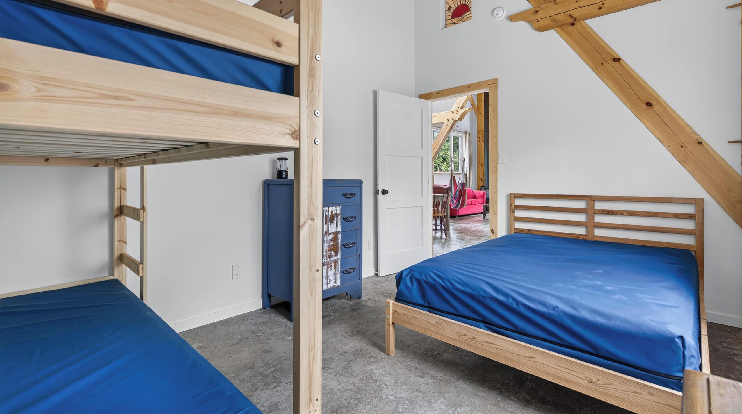 A room with bunk beds, a desk, and a chair.