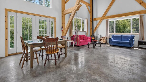 A spacious living area with a dining table, chairs, a sofa, and a fireplace. - The Enlightened - Retreat Under the Megantic Stars (Notre-Dame-des-Bois)