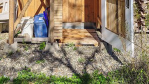 A wooden structure with a metal tank, a door, and a gravel path. - The Enlightened - Retreat Under the Megantic Stars (Notre-Dame-des-Bois)