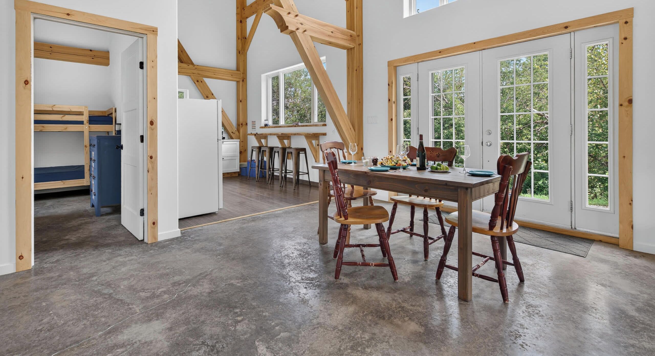 A spacious kitchen with a dining area, wooden beams, and large windows.