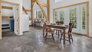 A spacious kitchen with a dining area, wooden beams, and large windows. - The Enlightened - Retreat Under the Megantic Stars (Notre-Dame-des-Bois)