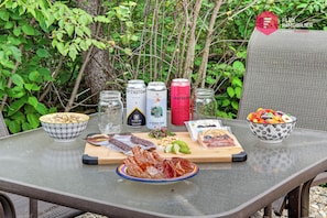 Mesa posta ao ar livre com comida, bebidas e acompanhamentos.