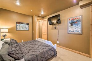 Ein Schlafzimmer mit einem Bett, einem an der Wand montierten Fernseher und zwei gerahmten Postern.