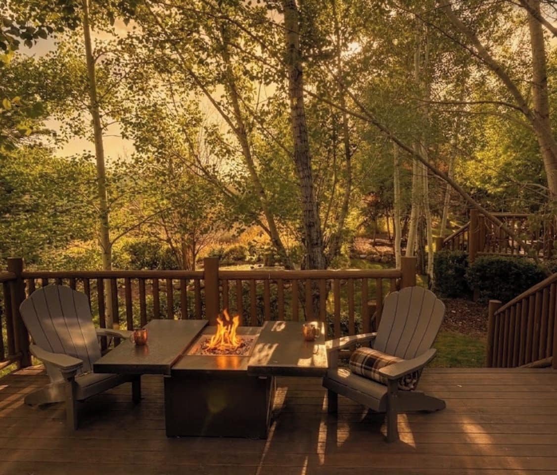 An outdoor deck with a fire feature, seating, and a wooden railing.