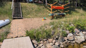 A wooden deck, a ladder, a small boat, a children's play area, and a wooden structure with a roof. - 4-bedroom family lake house near Park Rapids with air conditioning (Nevis)
