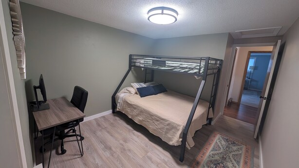 A room with a bunk bed, a desk with a chair, a computer, and a patterned rug. - 4-bedroom family lake house near Park Rapids with air conditioning (Nevis)