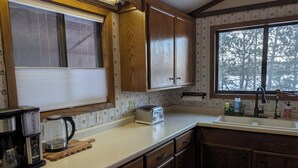 A kitchen with wooden cabinets, a window with blinds, a toaster, and a coffee maker. - 4-bedroom family lake house near Park Rapids with air conditioning (Nevis)