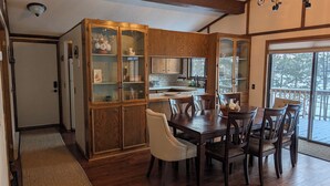 A dining area with a wooden table and chairs, a kitchen with wooden cabinets, and a view of the outdoors through a glass door. - 4-bedroom family lake house near Park Rapids with air conditioning (Nevis)