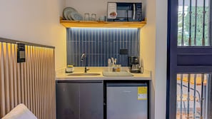 A compact kitchenette with a microwave, coffee maker, and a small refrigerator. - Primavera Lofts (Medellín)