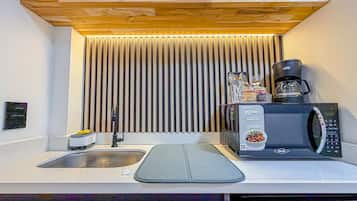 A compact kitchen with a built-in microwave, a coffee maker, and a sink.