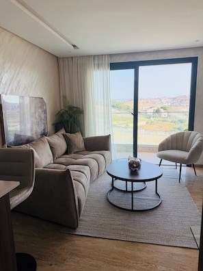 A modern living room with a sofa, a round coffee table, and a chair. - Cozy 2-Bedroom Apartment in Center of Tangier - AC & Terrace (Tangier)