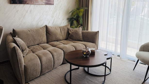 Un salon moderne avec un canapé d’angle, une table basse et une plante en pot.