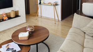 Un salon moderne avec une table basse ronde, un canapé, un téléviseur et une petite table agrémentée d’objets décoratifs.