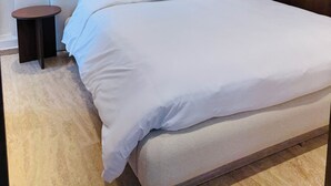 Une chambre moderne avec un grand lit, une table de chevet ronde et une armoire en bois.
