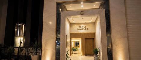 The entrance to Triple Towers hotel with a modern facade and a welcoming interior.