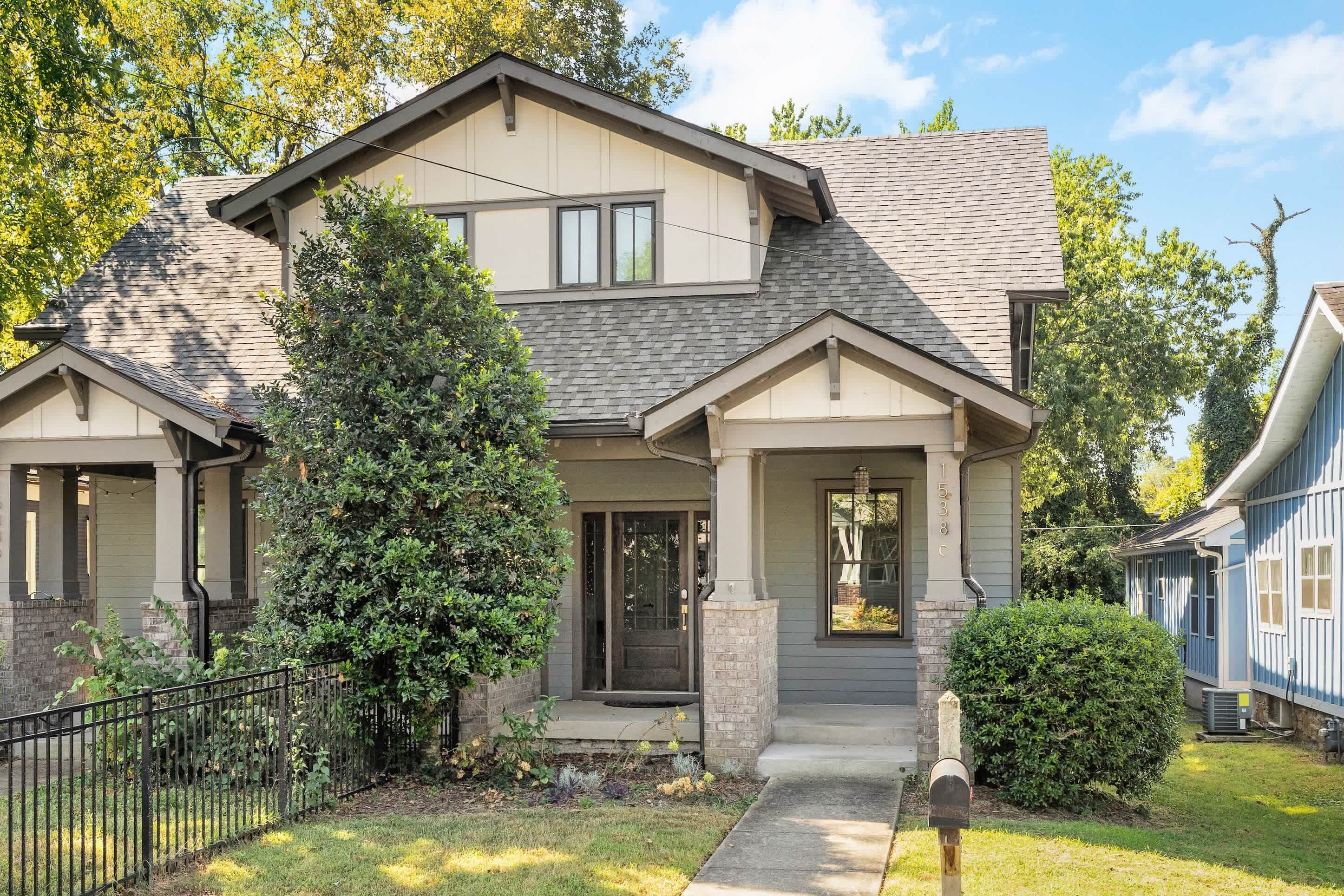 A two-story house with a front porch, a mailbox, and a small garden.