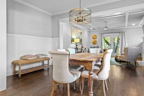 A dining area with a wooden table, upholstered chairs, a bench, and a decorative ceiling light. - Fully Furnished 3BR East Nashville Home | 30+ Days (Nashville)