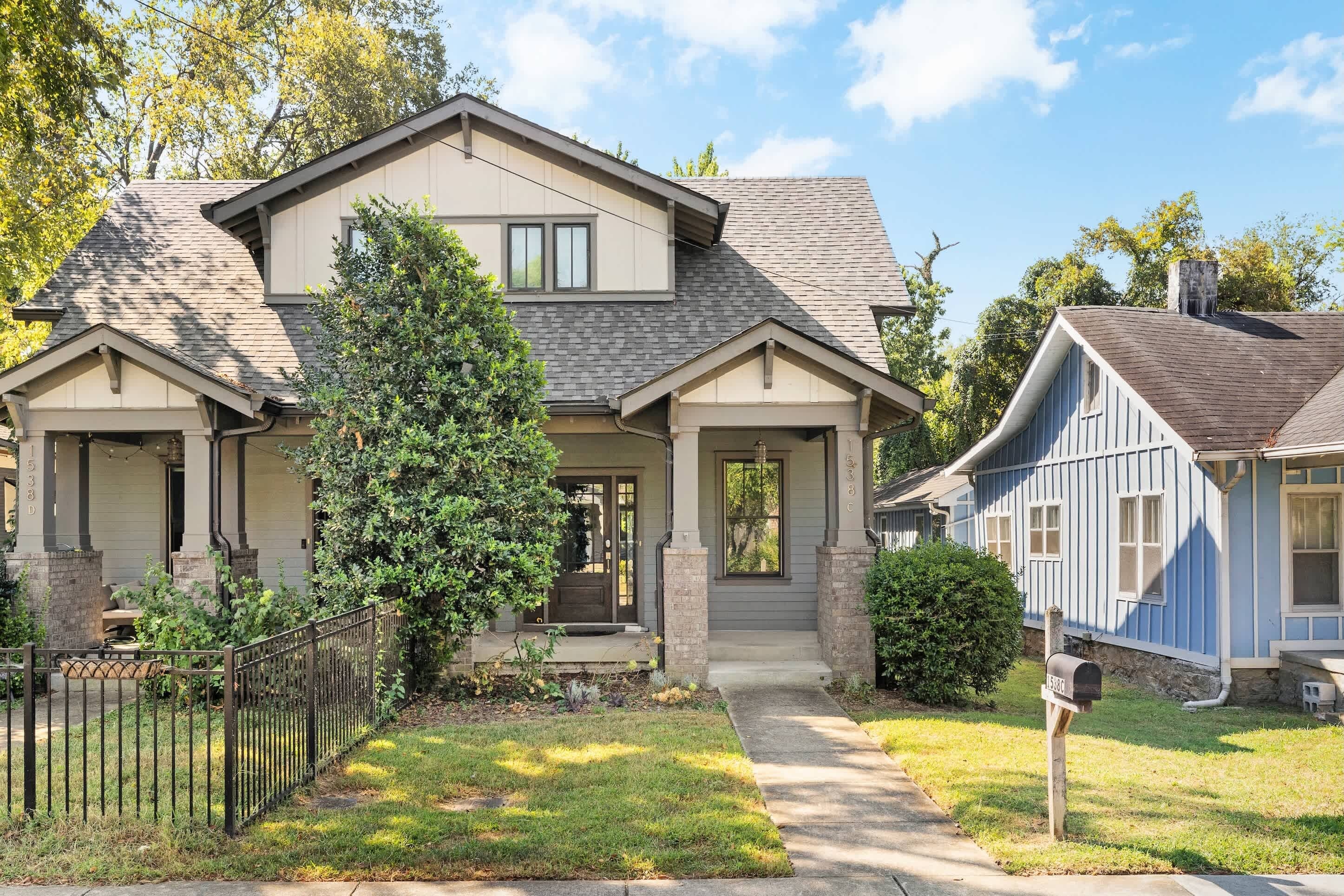 A two-story house with a front porch, a mailbox, and a well-maintained lawn.