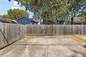A concrete driveway leading to a wooden fence with a gate. - Fully Furnished 3BR East Nashville Home | 30+ Days (Nashville)